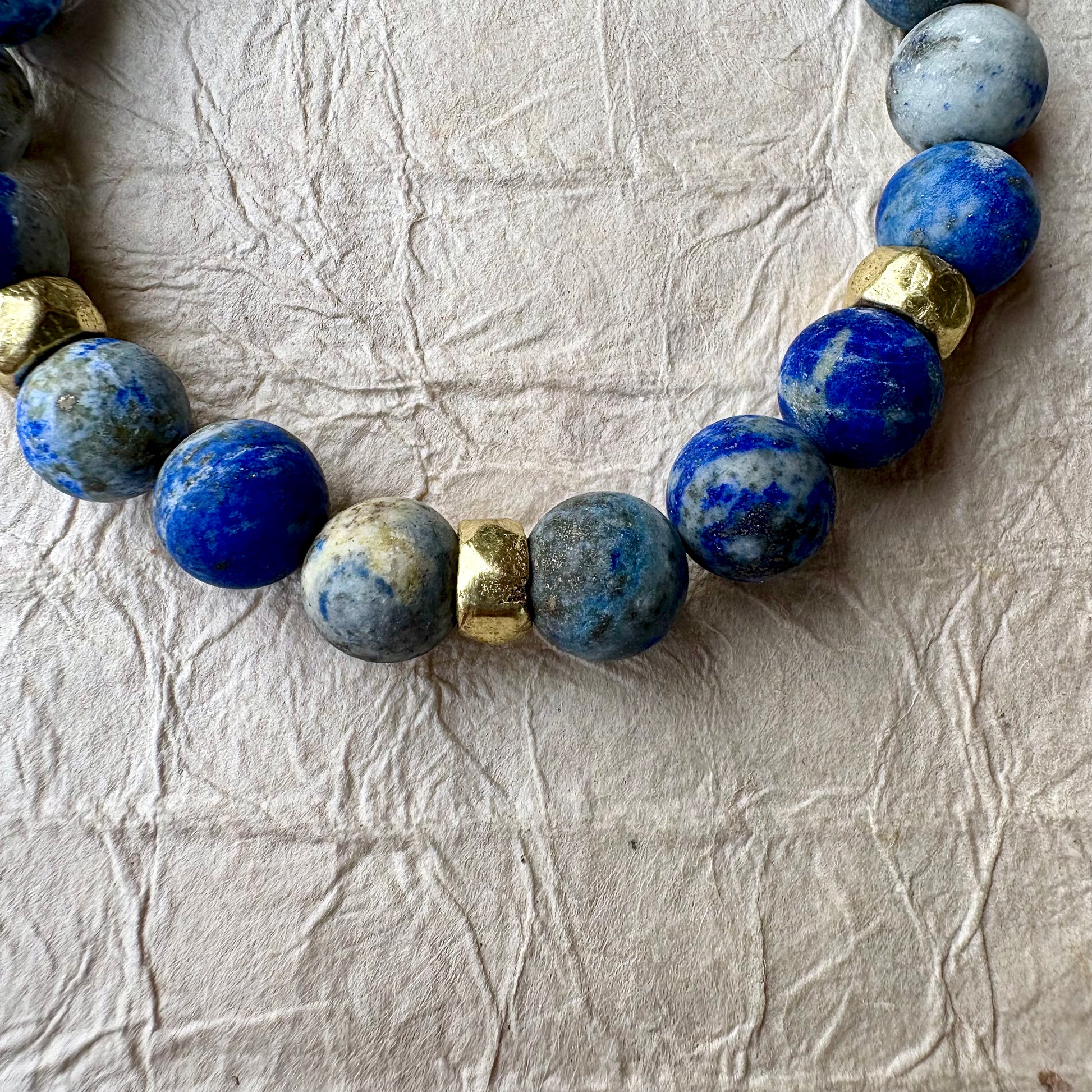 A beaded stretch bracelet made of blue lapis lazuli stones with gold spacer beads. 
