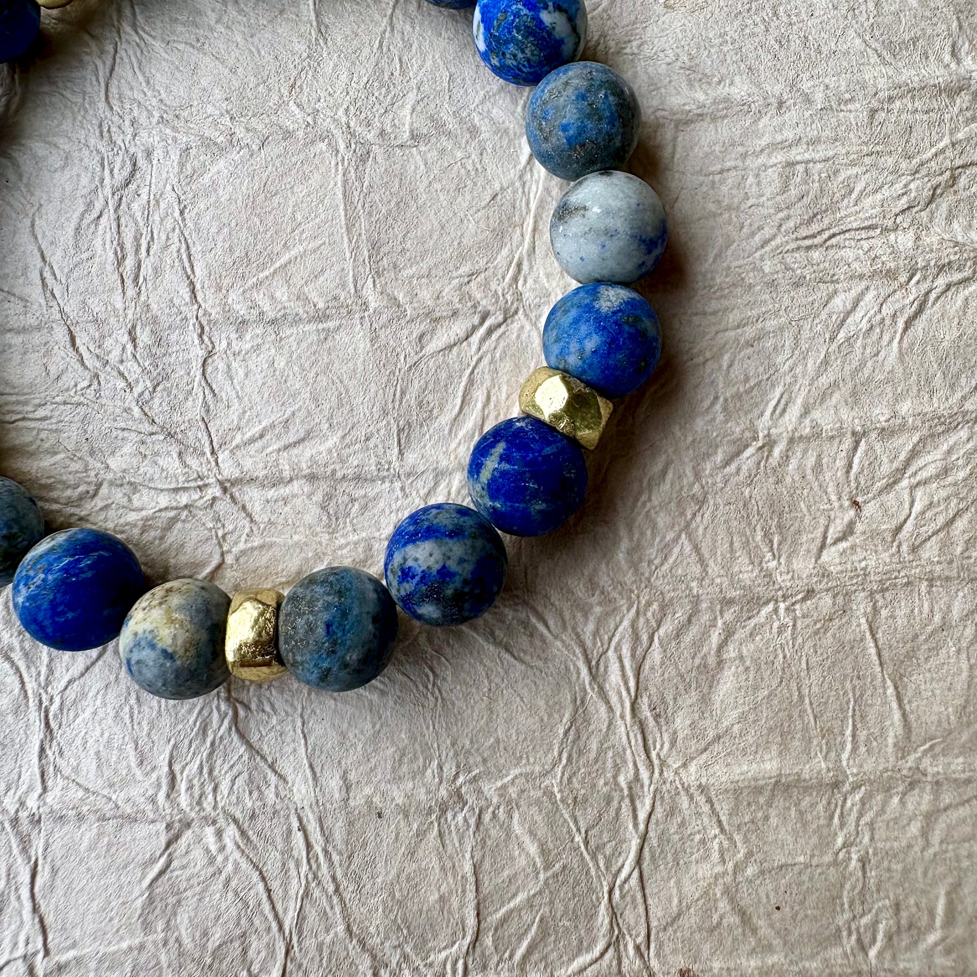 A beaded stretch bracelet made of blue lapis lazuli stones with gold spacer beads. 