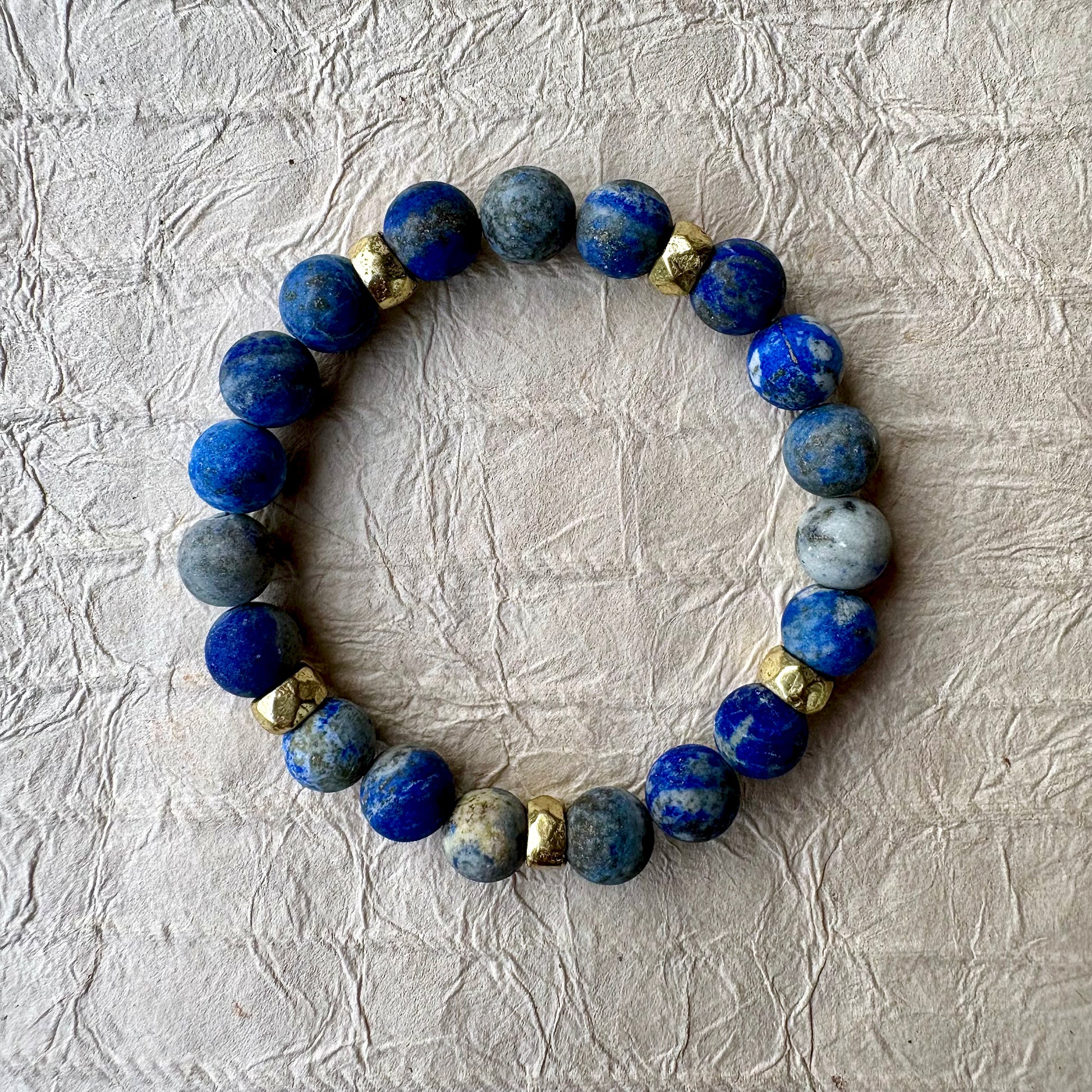 A beaded stretch bracelet made of blue lapis lazuli stones with gold spacer beads. 