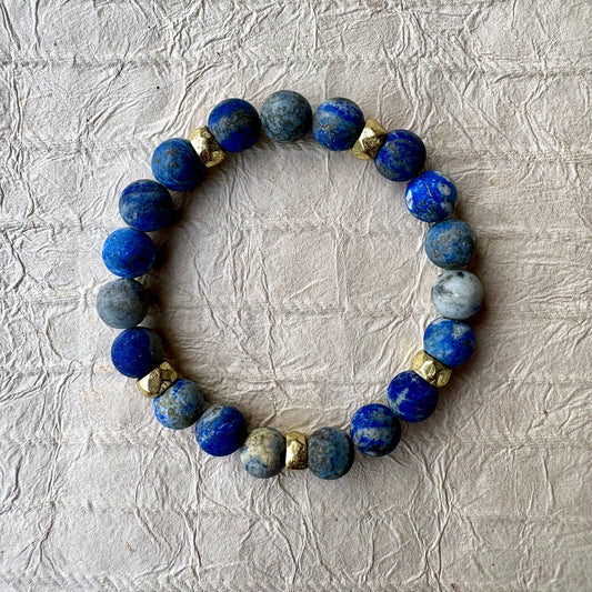 A beaded stretch bracelet made of blue lapis lazuli stones with gold spacer beads. 