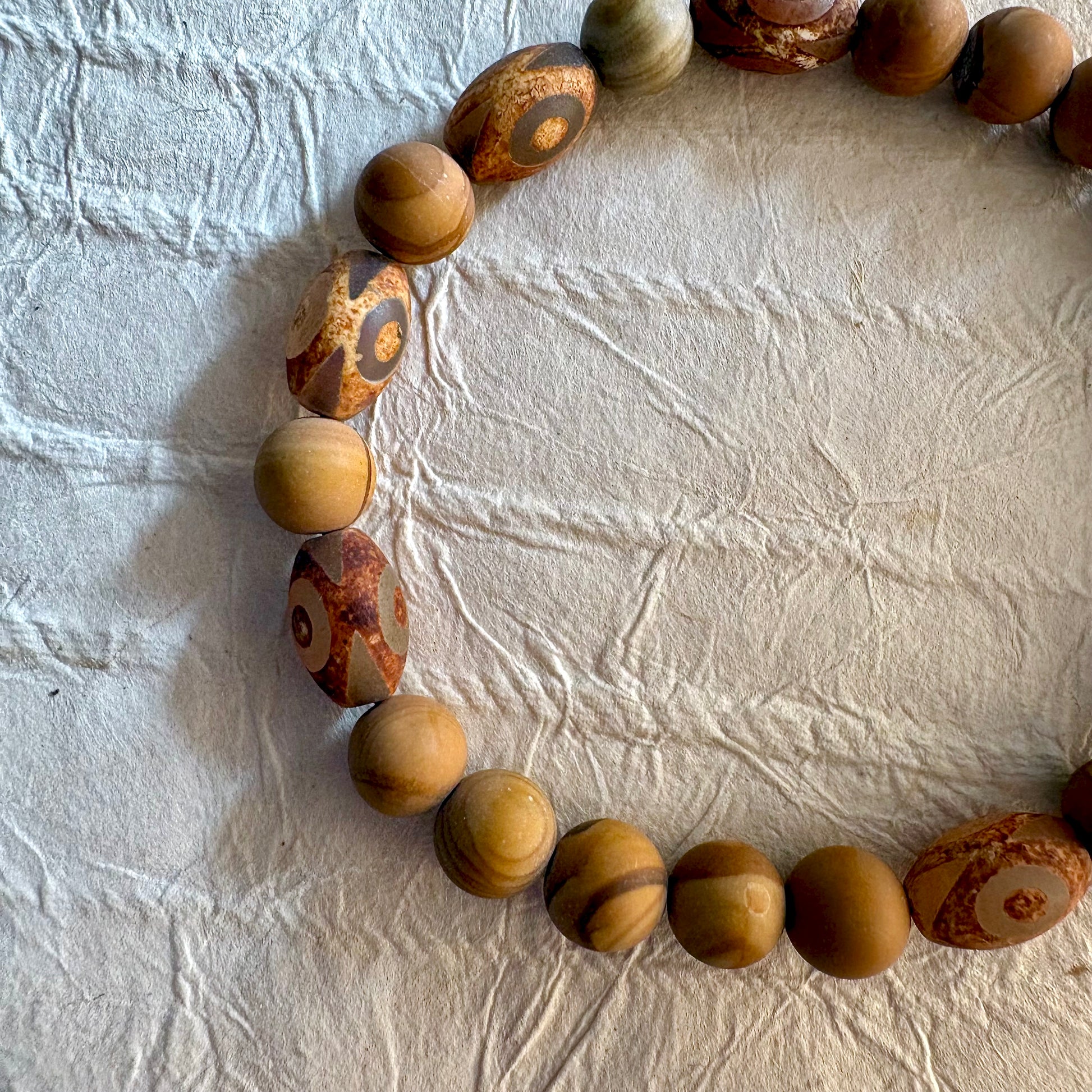 A beaded stretch bracelet made of natural wood beads with distinctive swirling grain patterns.