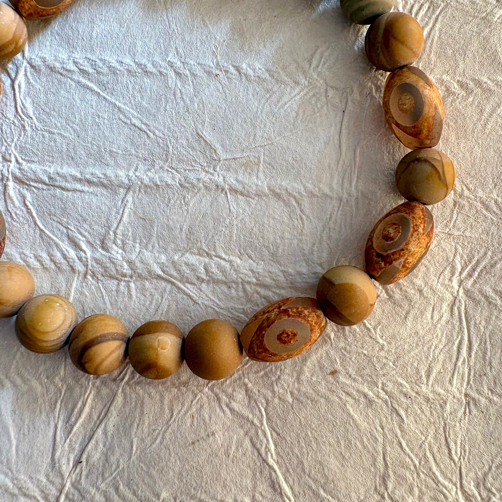 A beaded stretch bracelet made of natural wood beads with distinctive swirling grain patterns.