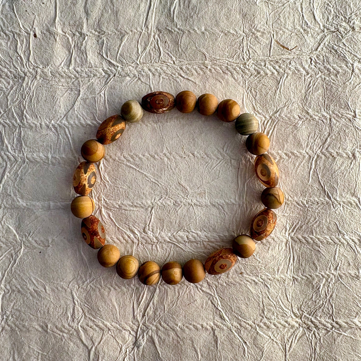A beaded stretch bracelet made of natural wood beads with distinctive swirling grain patterns.