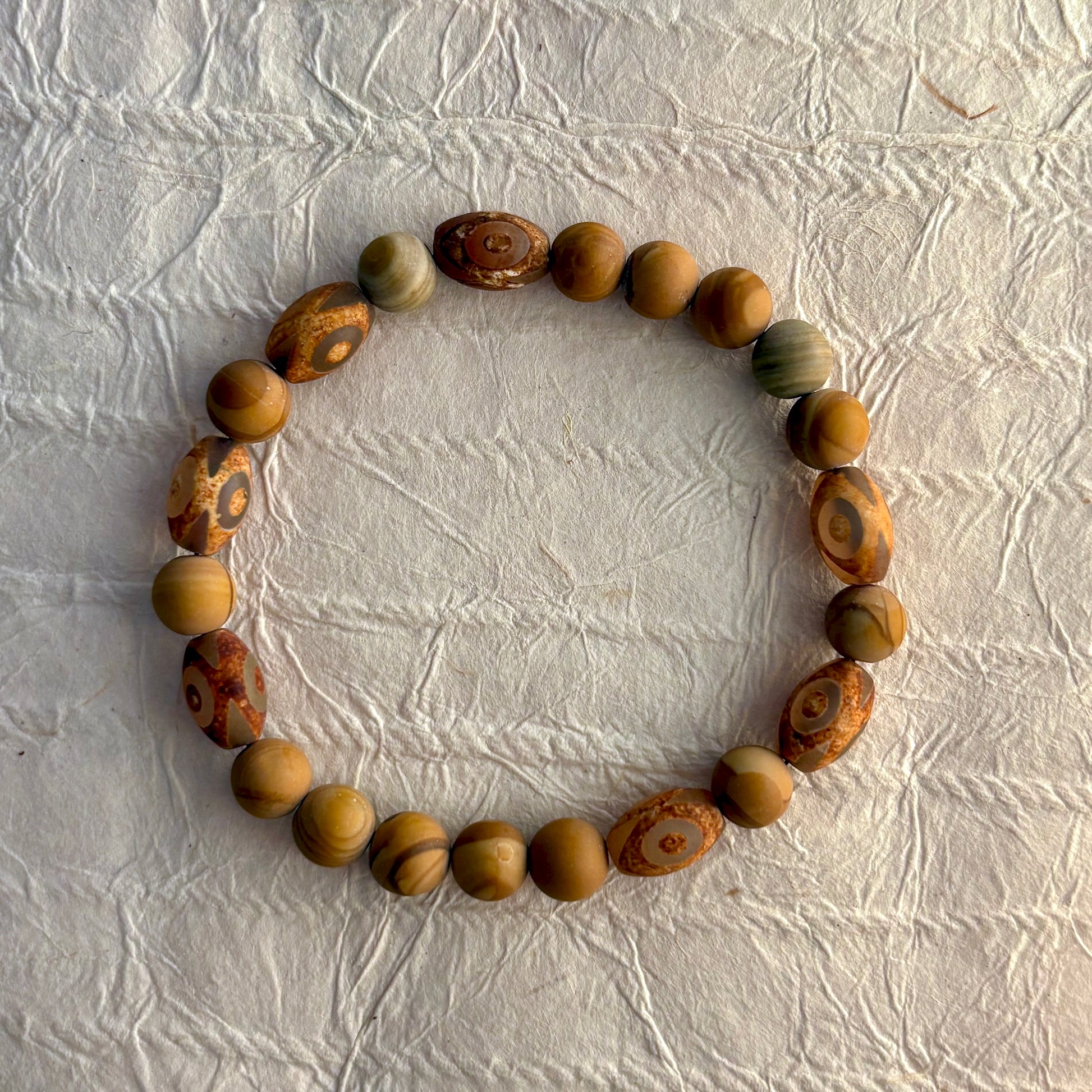 A beaded stretch bracelet made of natural wood beads with distinctive swirling grain patterns.