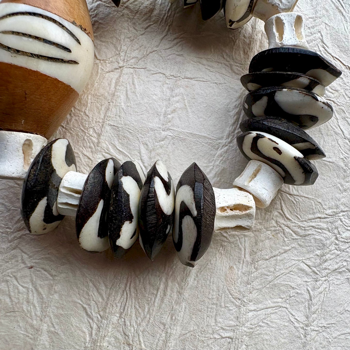 A close-up of a beaded necklace or bracelet featuring alternating black and white marbled beads.